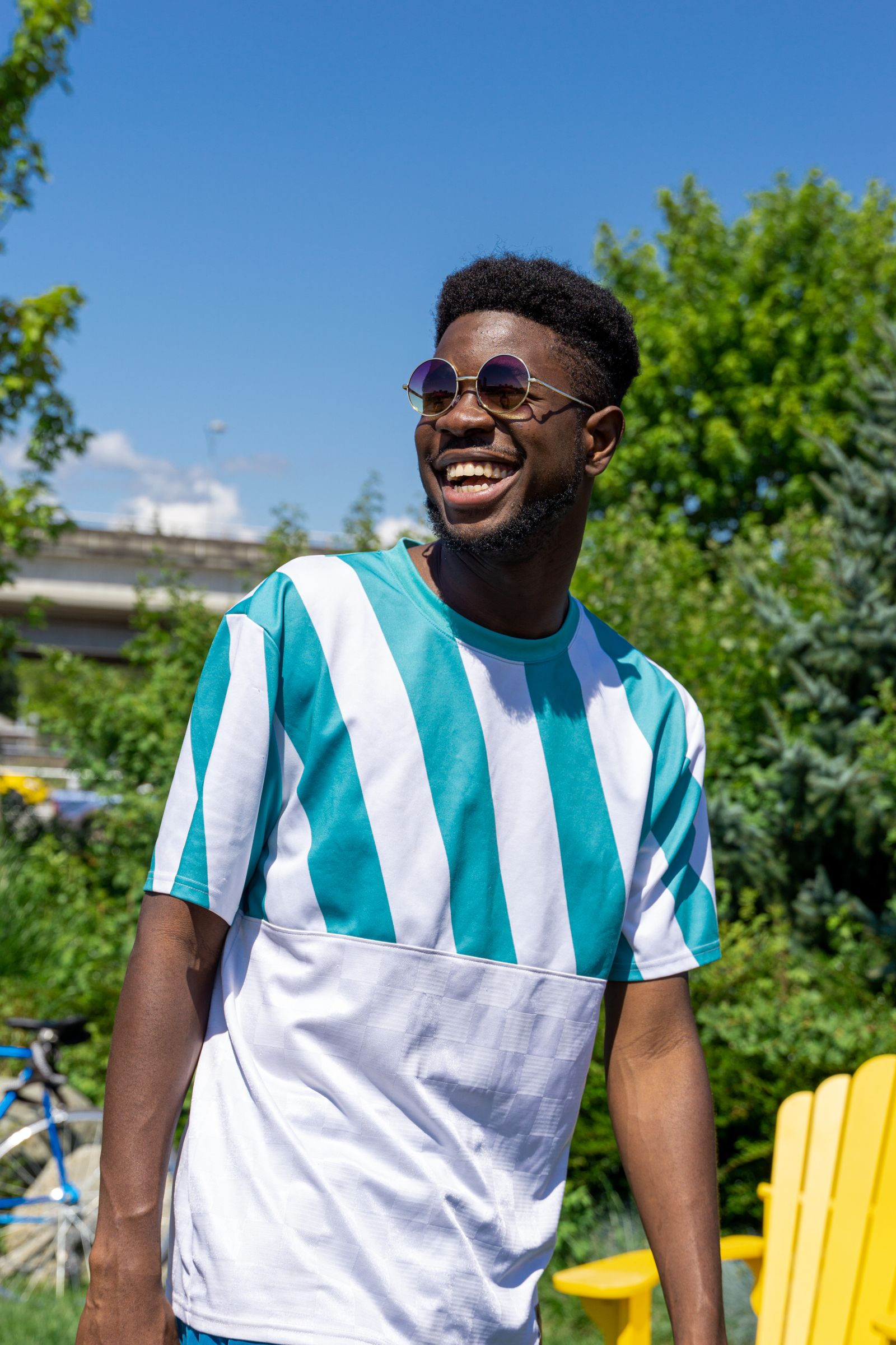 Person laughing outdoors in round mirrored sunglasses